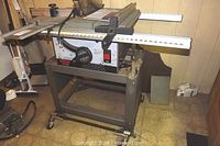 Photo showing Ryobi BT3000 table saw mounted on metal work stand with caster wheels.