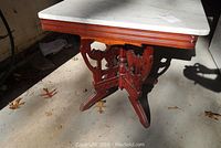 View showing white marble tabletop and the top edge of the wooden frame with carved and reeded accents.