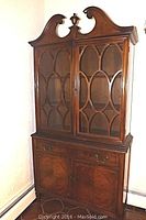 View of the full cabinet showing the decorative top, fretwork glass doors, drawer, and lower cupboard doors.