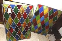 Both stained glass panels standing next to each other showing diamond pattern and multicolor glass pieces in tin framing.
