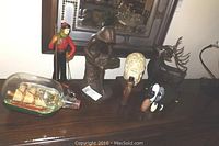 Photo showing the full collection of figurines displayed on a wooden surface, including the skier figure, metal sculptures, carved animal heads, and smaller figurines.