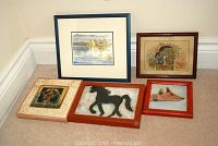 Overview of five framed artworks arranged on carpeted floor showing diverse styles including watercolor paintings and metal horse art.
