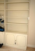 Full view of the painted wood bookcase with open shelves and lower cabinet with two doors, showing wear.
