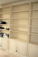 Full view of the white painted wooden bookcase with open shelves and lower cabinets, showing overall wear and paint chipped areas.