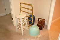 Full lot shot showing all items against beige wall: white stool, brass towel heater, sewing box with contents, light blue plastic basin, dark blue garbage pail, framed decor, blue container, and hair dryer on floor.