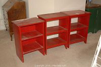 Three red wooden bookcases of varying sizes placed side by side on carpet flooring showing overall condition.