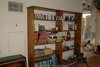 Wide view of tall wood cabinet with multiple shelves containing books and decorative items
