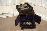 Chest opened showing top tray with silver spoons
