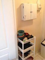 White plastic shelving unit with multiple garden pots of various sizes and colors including green and terracotta pots.