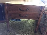 Front view of wooden side table showing two drawers with metal handles and tapered legs.