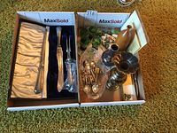 Two boxes shown from above: one with Birks carving set and the other with assorted glassware, spoons, cheese knives, and metal vase.