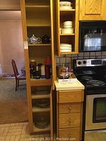 Panoramic view showing wooden kitchen shelves and cabinets with various kitchen items including thermoses, pie dishes, glassware, and baking dishes.