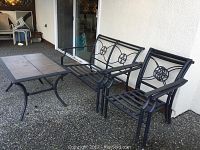 Metal framed bench, two chairs, and a square tiled outdoor table shown from the front on a patio.