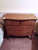 Full frontal view of antique dresser showing four drawers, wood grain, and brass handles.
