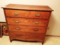 Front view of four drawer solid wood dresser showing wood grain and brass handles