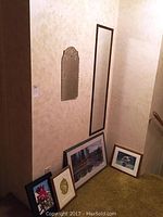 Wide view of five mirrors leaning against wall with various shapes and sizes visible.