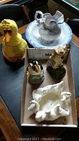 Set of assorted bird and human figurines along with yellow bird cookie jar arranged on a table