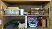 Wooden shelf with miscellaneous camping and kitchen items including plastic container, dishes, and boxed hibachi set