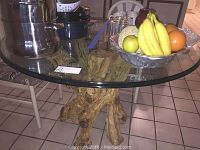 Full view of round glass top table with cookware and fruit bowl on surface