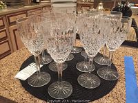 Front view of 12 crystal water goblets arranged in a circle on a black placemat