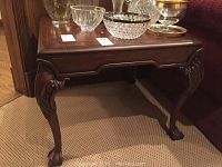 Wood side table angled front view showing leather look top and carved legs