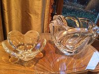 Small Tiffany dish at left and large Steuben bowl at right, both on wood surface against drapery backdrop.