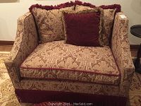 Front view of oversized armchair showing paisley-patterned upholstery, fringe trim, and cushions