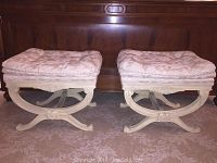Photo showing paired matching bedroom benches with white wooden frames and embroidered cushioned tops placed on carpet.