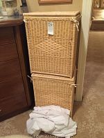 Two natural wicker hampers stacked with cloth liners and a white fabric mattress cover in front.