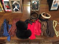 Overview photo showing the full lot on wooden tabletop with several framed photos in background, including diverse leather gloves in black, brown, red, blue, and an assortment of headbands in black, beige, and yellow braided cord.