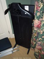Full view of black Corby electric trouser press standing upright with hanger and power cord visible