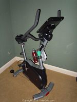 Front right view of entire bike showing frame, console, handlebars, water bottle holder and adapter on the floor