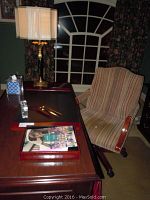 Full view of desk and upholstered rolling chair, showing desk accessories and lamp.