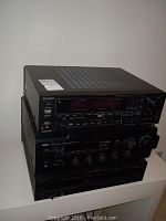 Stack of three black stereo components including a Sony unit on top with red digital display and Yamaha and Toshiba below.