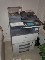 Full view of the Konica Minolta bizhub 200 copier showing its paper trays, control panel, and extra toner on top.