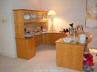 Full view of wrap around L-shaped wooden desk with hutch and lamp on desk top, showing ample work surface and storage compartments.