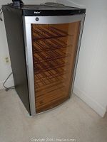 Wine refrigerator showing front view with multiple metal racks inside and tinted glass door.