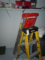 Yellow Husky 3-step ladder and aluminum Werner extension ladder pictured together in a corner of a room.