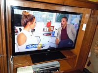 Front view of LG television with screen on display inside a wood cabinet