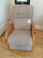 Front view of beige fabric recliner with wood arm rests