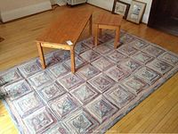Photo showing the pine coffee table and end table positioned on the area rug, displaying the natural pine wood finish, some wear marks, and the rug's patterned design.