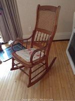 Full view of the rocking chair showing wood frame, wicker back, and seat mat.