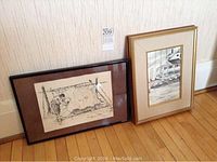 Photo showing both framed artworks leaning against a wall on a wood floor, including watercolour and ink print.