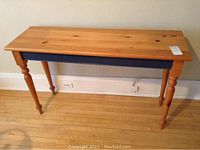 Front view of pine hall table with natural wood tabletop and blue painted apron with turned legs.