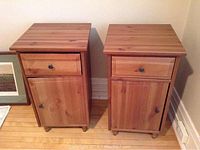 Front view of two wooden night stands showing the drawer and cupboard doors with knobs.