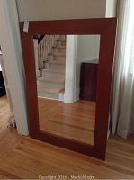 Front view of the large rectangular mirror with wood frame leaning against a wall, showing its size and frame color.