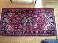 Red oriental rug with central medallion laid flat on hardwood floor