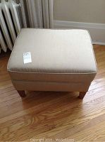Top angled view of ottoman showing cushion and legs