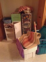 Overall lot showing storage bins, wire basket stand with baskets, small cabinets, wooden crate and linens stacked.