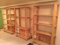 Three wooden shelving units placed side by side against wall showing overall lot contents and structure.